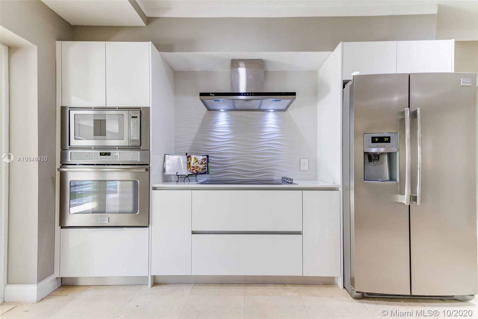 6030 Alton Road Miami Beach, FL 33140 - Photo 10 of 51 a kitchen with white cabinets and stainless steel appliances