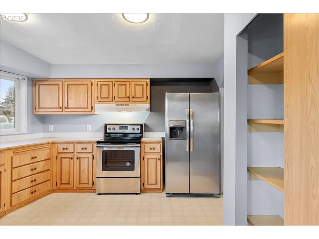 a kitchen with stainless steel appliances granite countertop a stove a sink and a refrigerator with wooden cabinets