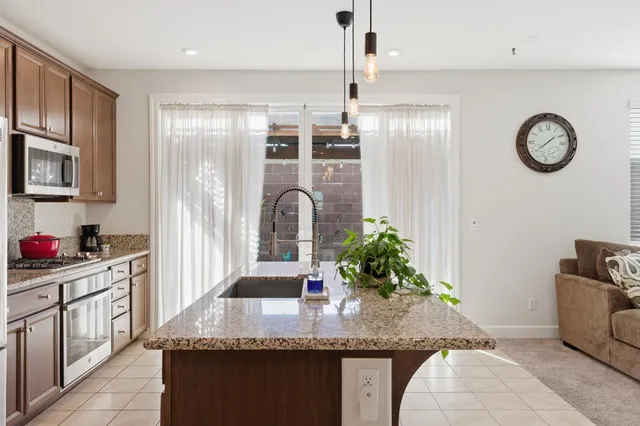 a kitchen with stainless steel appliances granite countertop a sink a stove and a wooden floors