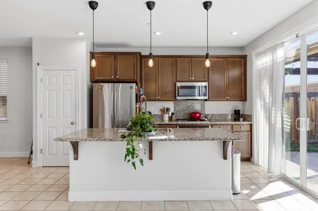a kitchen with stainless steel appliances granite countertop a sink a stove and a refrigerator