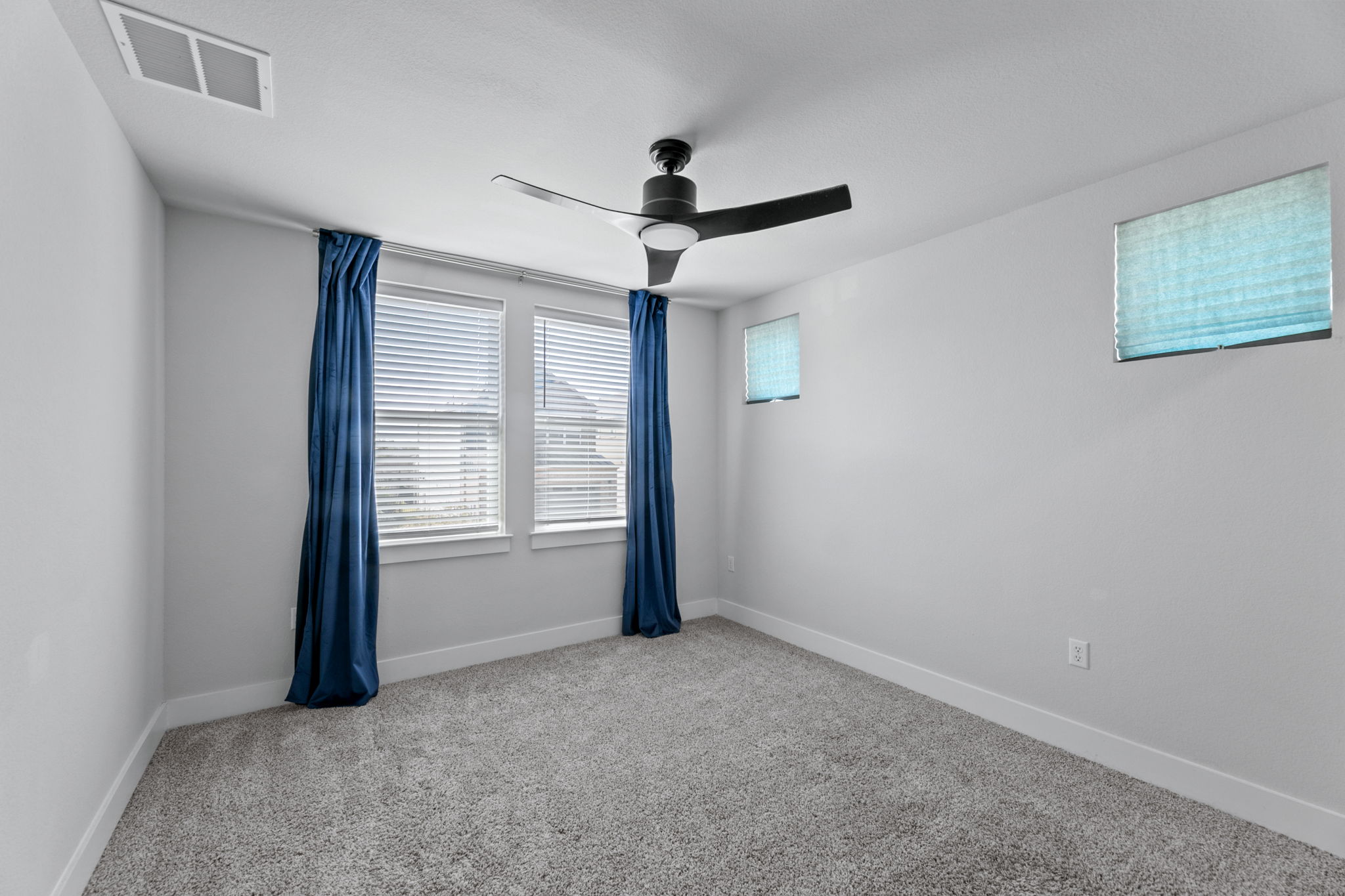 7312 Travertine Spring Drive Austin, TX 78744 - Photo 28 of 32 A well-lit bedroom features plush carpeting and a modern ceiling fan, offering a comfortable personal retreat.