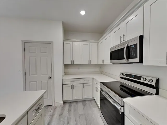 a kitchen with stainless steel appliances a stove a microwave and white cabinets