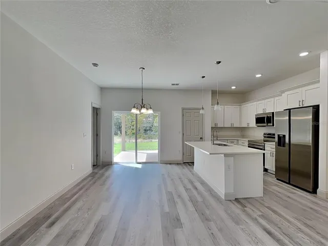 a large kitchen with a wooden floor and stainless steel appliances