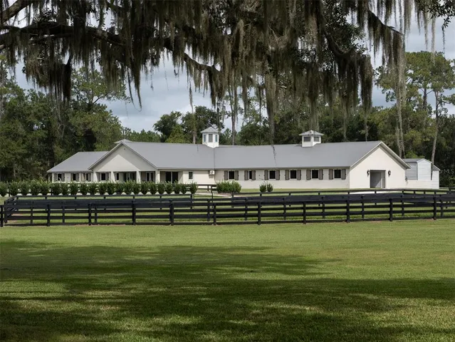 a aerial view of a house next to a lake with lawn chairs under an umbrella