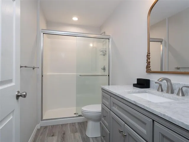 a bathroom with a granite countertop sink toilet a mirror and shower