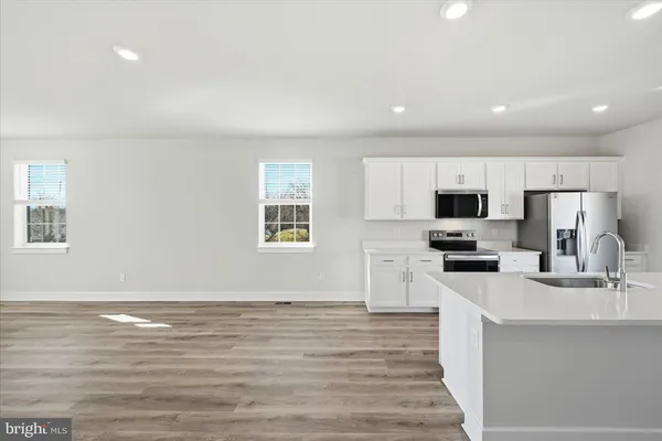 a large kitchen with cabinets wooden floor and stainless steel appliances