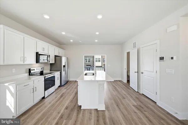 a kitchen with stainless steel appliances a refrigerator a stove a microwave and white cabinets