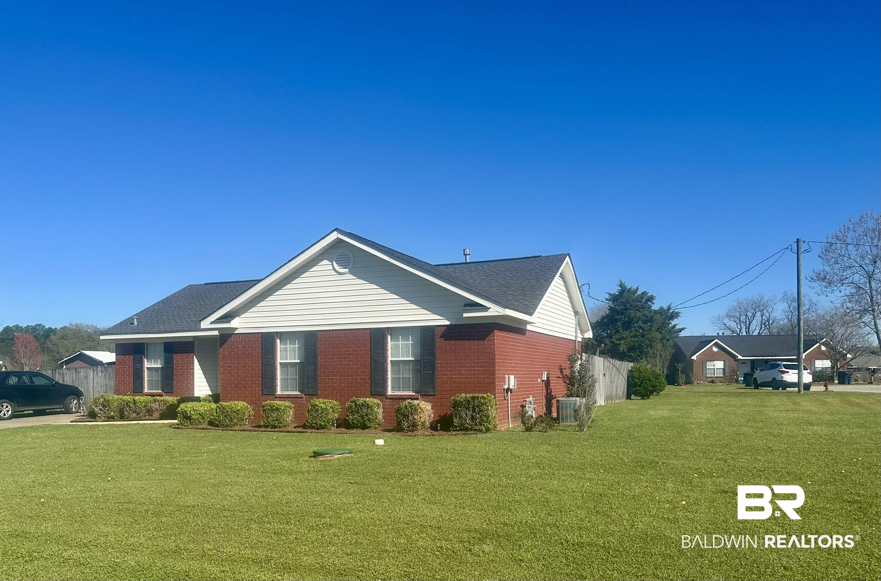 View of side of home with a yard, brick siding, cooling unit, and fence