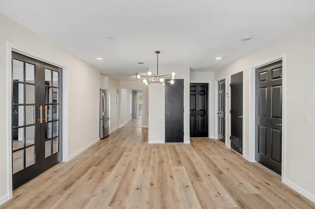 a view of a hallway with wooden floor and chandelier