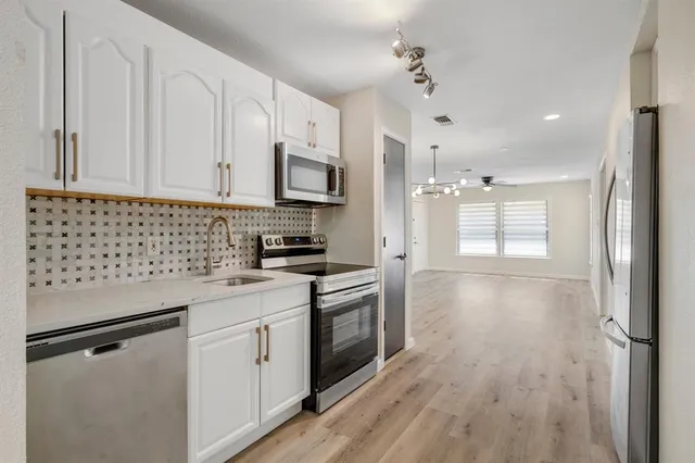 a kitchen with stainless steel appliances a stove a sink and a refrigerator