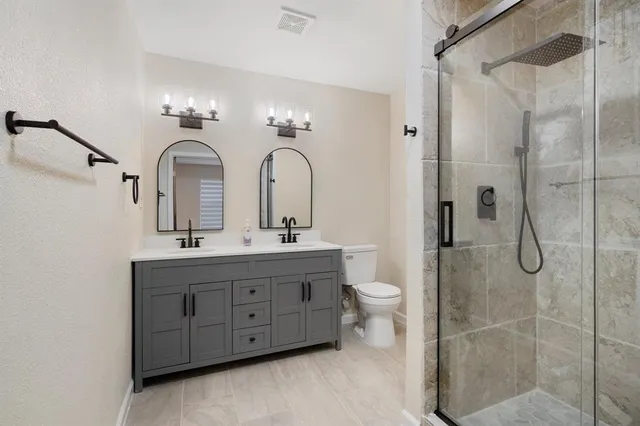 a bathroom with a double vanity sink toilet and shower
