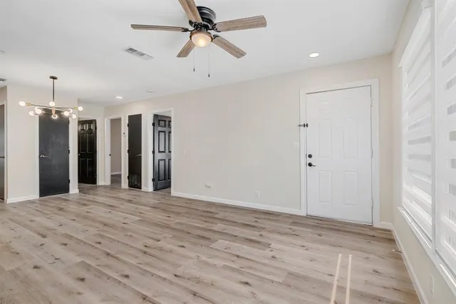 a view of a hallway with a chandelier fan and wooden floor