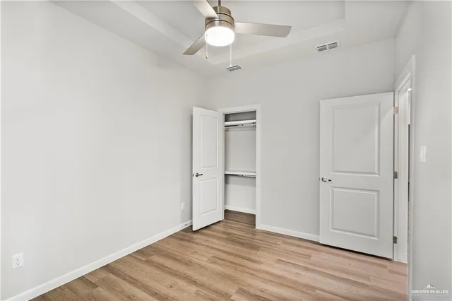 an empty room with wooden floor closet and windows