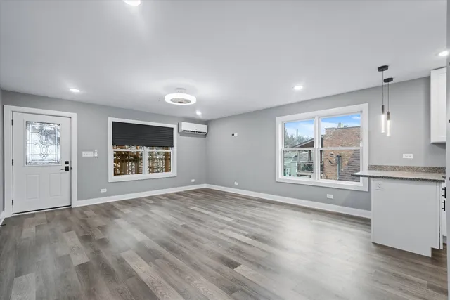 a view of an empty room with a window and wooden floor