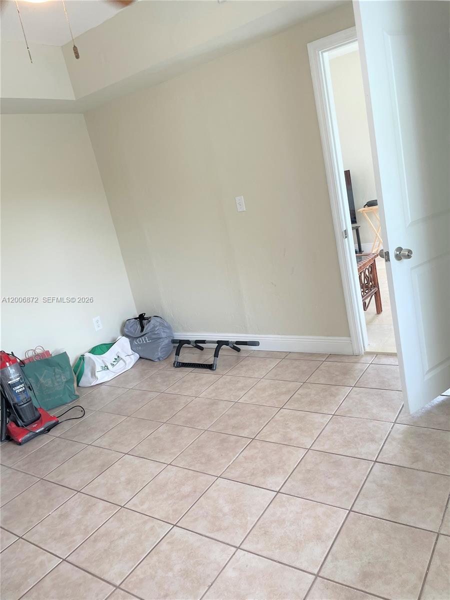 5116 Southwest 57th Avenue, Unit B Miami, FL 33155 - Photo 12 of 26 an empty room with wooden floor and fan