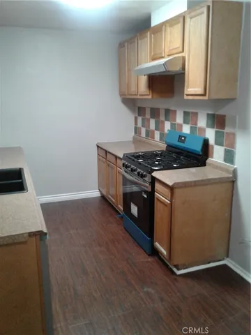 a kitchen with granite countertop wooden floors and a stove