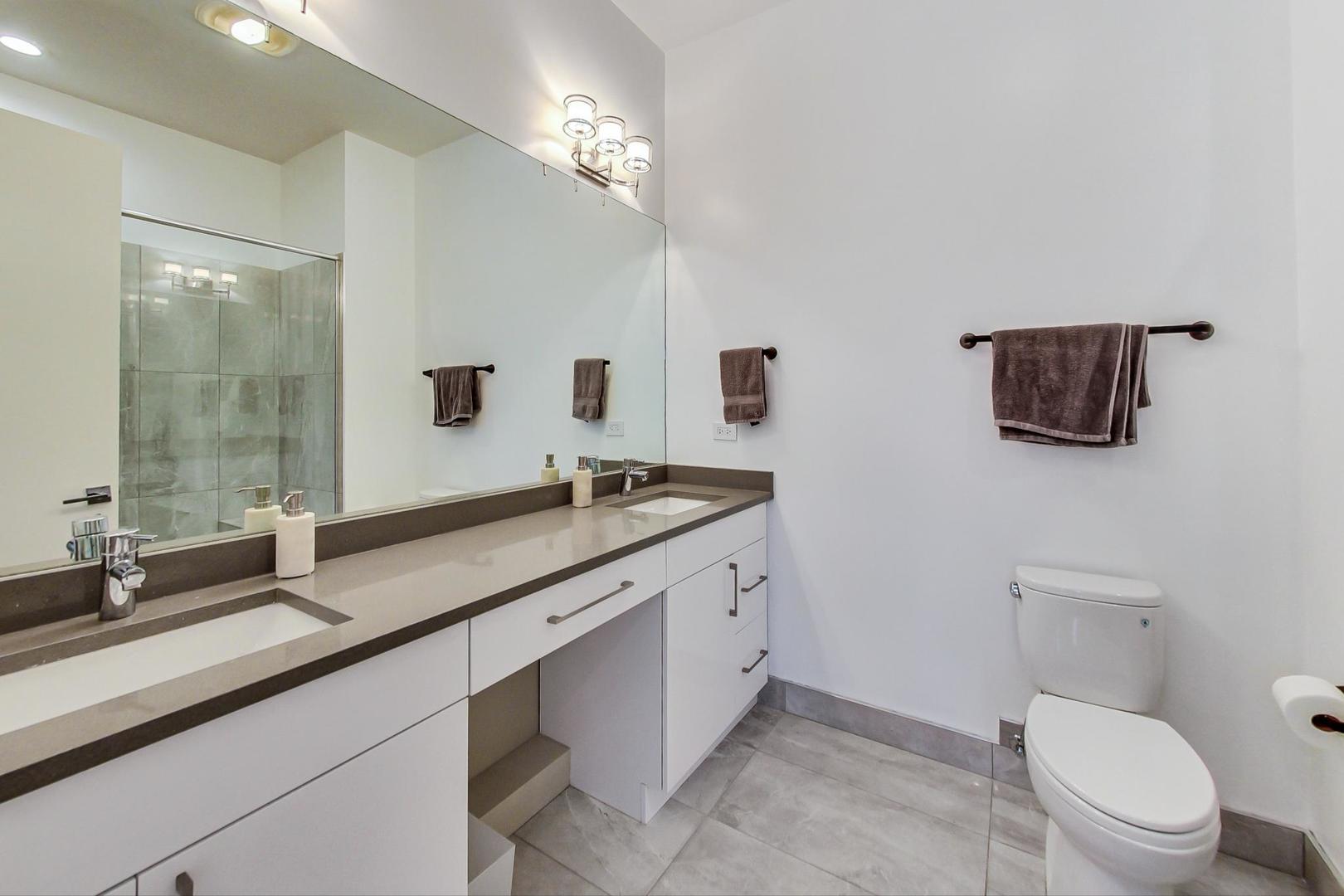 4042 North Pulaski Road, Unit 3W Chicago, IL 60641 - Photo 16 of 33 a bathroom with a granite countertop sink a toilet a mirror and shower