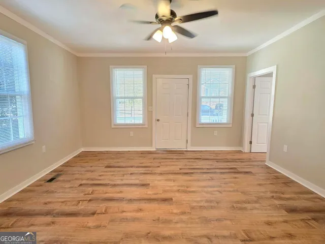 a view of an empty room with window and chandelier fan