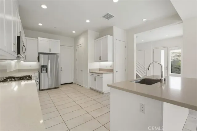 a kitchen with a sink white cabinets and appliances