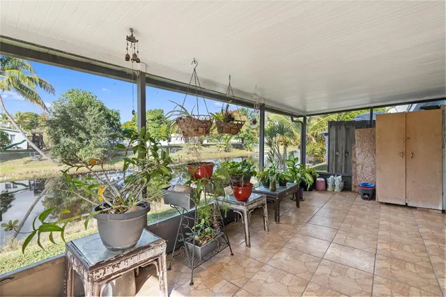 a room with lots of potted plants and large windows