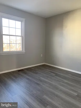 an empty room with wooden floor and window