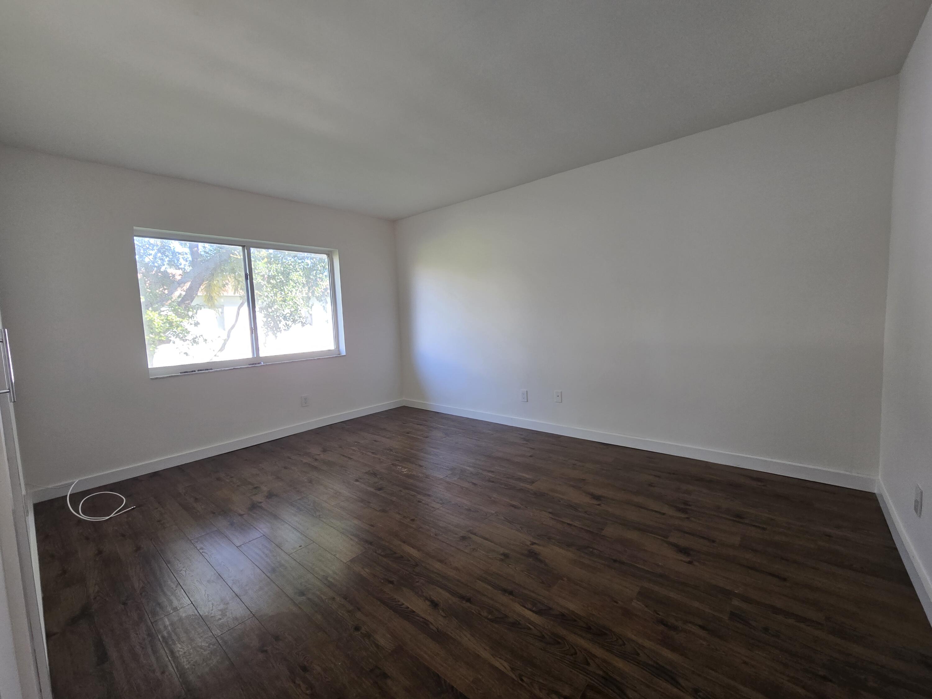 201 Southeast 6th Avenue, Unit 16 Pompano Beach, FL 33060 - Photo 9 of 10 a view of an empty room with wooden floor and a window