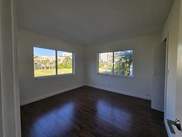 an empty room with wooden floor windows and entrance