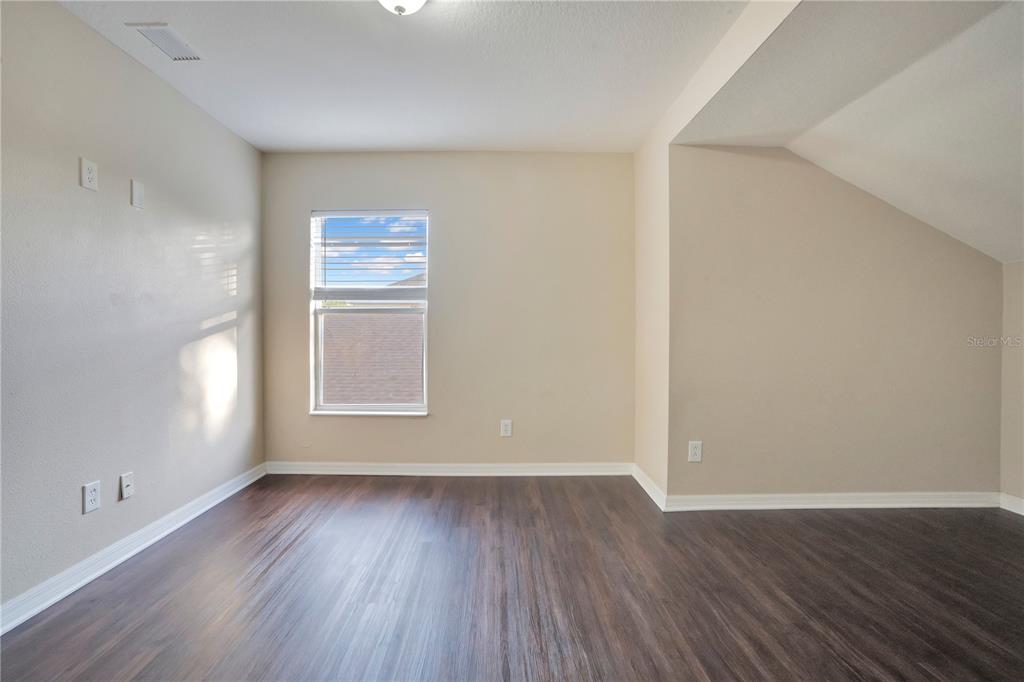 15031 Skip Jack Loop Lakewood Ranch, FL 34202 - Photo 22 of 27 an empty room with wooden floor and windows