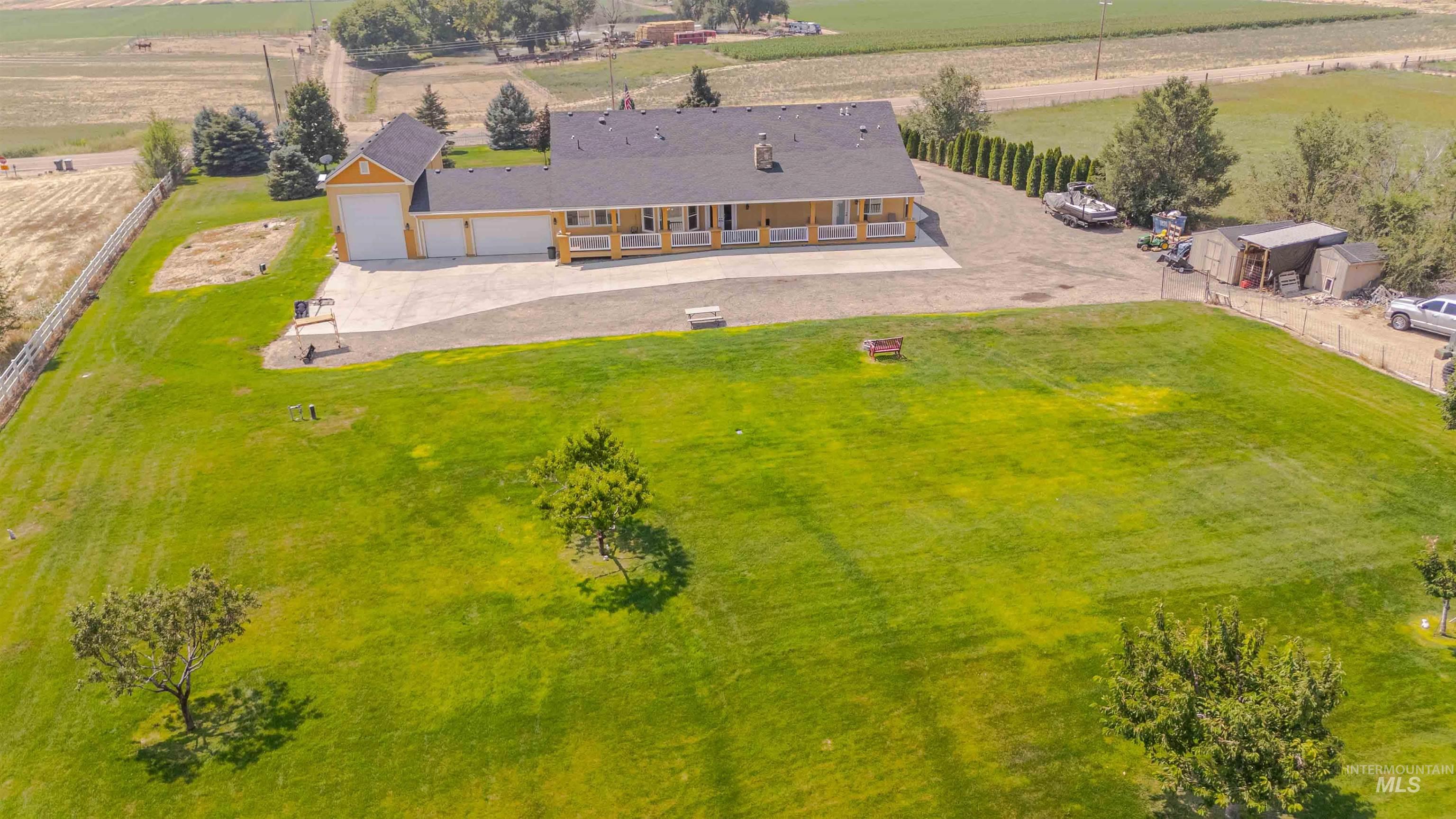 11378 Purple Sage Road Middleton, ID 83644 - Photo 47 of 50 Expansive green lawn framed by mature trees, featuring a white picket fence bordering a body of water in the background