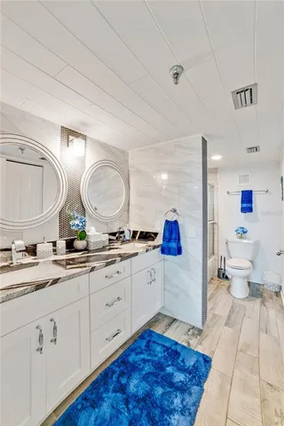 a spacious bathroom with a granite countertop sink mirror vanity and toilet