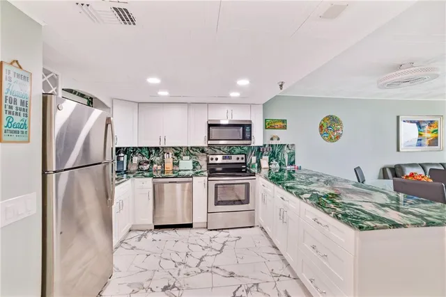 a kitchen with stainless steel appliances granite countertop a refrigerator a stove a sink a microwave a dining table and chairs with wooden floor