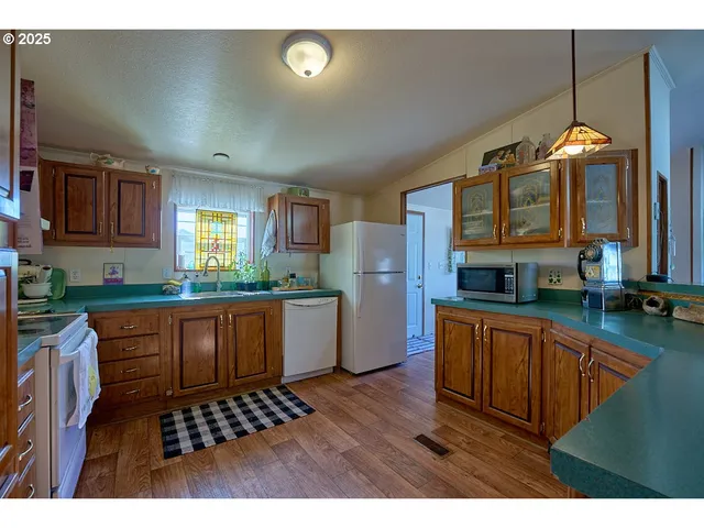 a kitchen with stainless steel appliances kitchen island granite countertop a stove a sink dishwasher and cabinets with wooden floor
