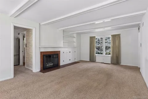 an empty room with windows and fireplace