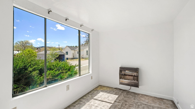 44 Shriver Street Eureka, UT 84628 - Photo 6 of 43 Expansive picture window, white painted walls, wall-mounted heater, light gray textured carpeting, and white baseboards