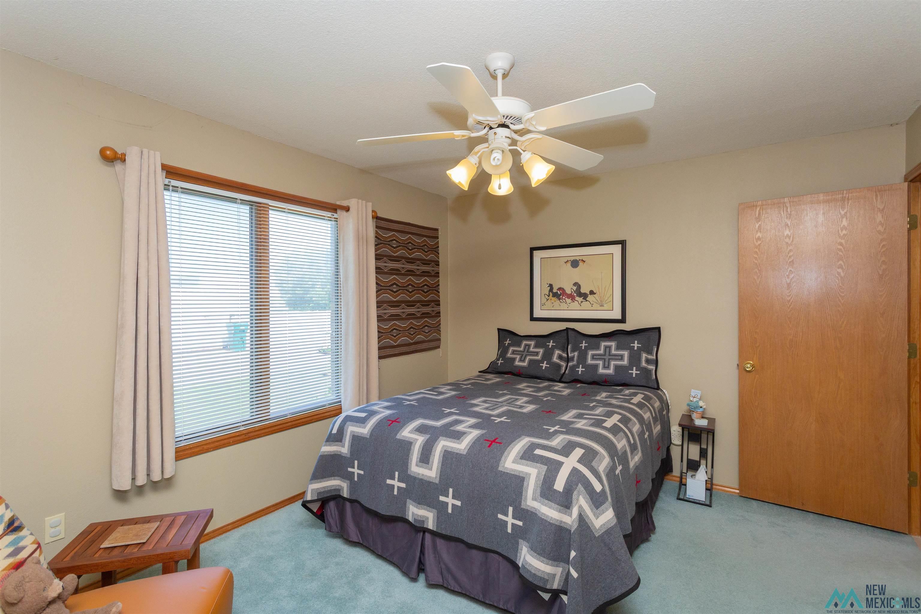 2012 South Haldeman Road Artesia, NM 88210 - Photo 26 of 96 Carpeted room featuring a window with blinds, a ceiling fan with integrated lighting, and a wood-finish door