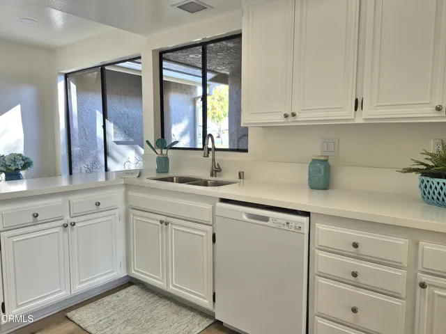 a kitchen with white cabinets and sink