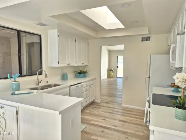 a large white kitchen with wooden floor