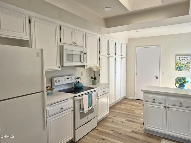 a kitchen with white cabinets and white appliances