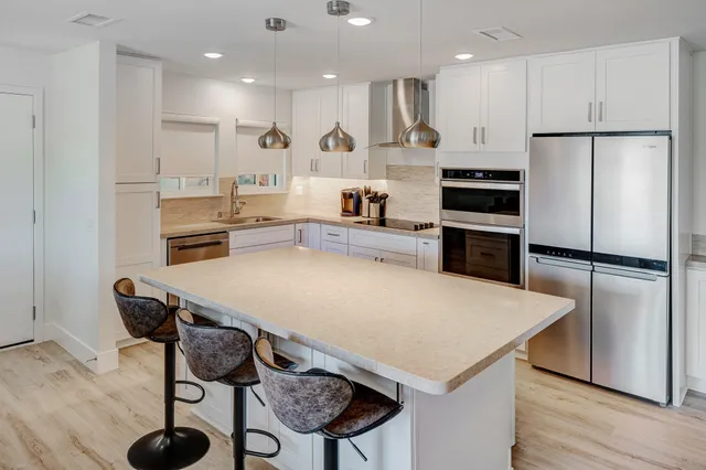 a kitchen with kitchen island a stove a refrigerator and a dining table with wooden floor