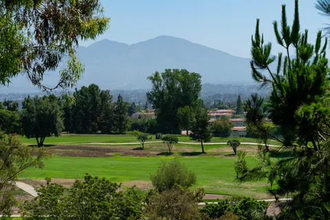 a view of a green field with mountains in the background