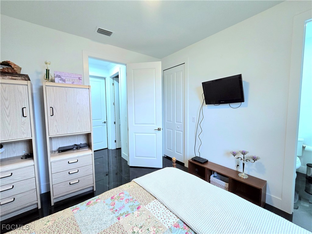 705 Harding Lane Lehigh Acres, FL 33936 - Photo 25 of 38 a bedroom with a bed and a flat tv screen in it