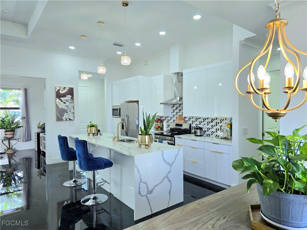 705 Harding Lane Lehigh Acres, FL 33936 - Photo 9 of 38 a kitchen with stainless steel appliances kitchen island granite countertop a dining table chairs and white cabinets