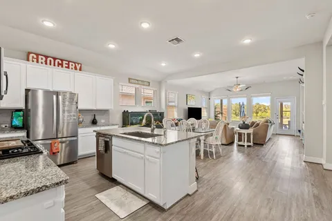 a kitchen with stainless steel appliances granite countertop a kitchen island hardwood floor and a refrigerator