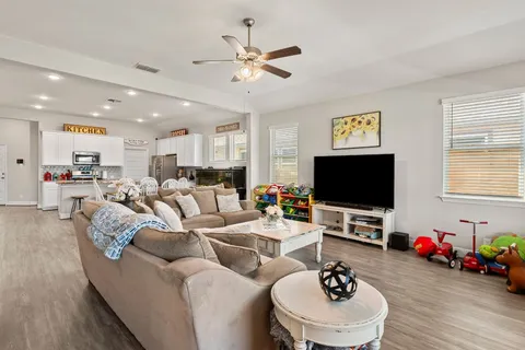 a living room with furniture kitchen view and a chandelier