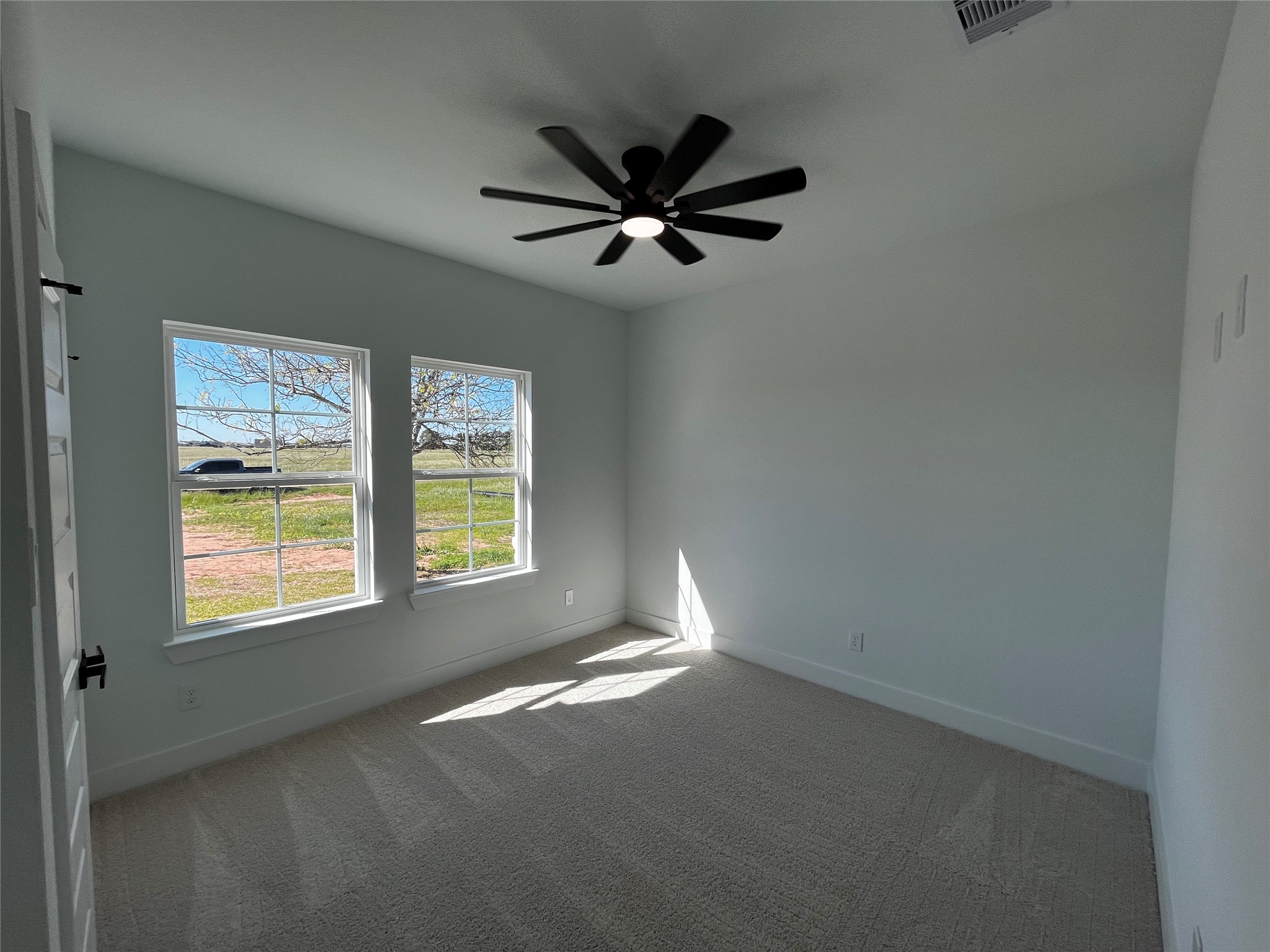 471 Buffalo Trail Angleton, TX 77515 - Photo 17 of 35 The first room to the left when walking in features a large window with views of a grassy landscape, allowing plenty of natural light. It has a neutral color palette, carpeted floor, and a modern ceiling fan, creating a bright and airy space.