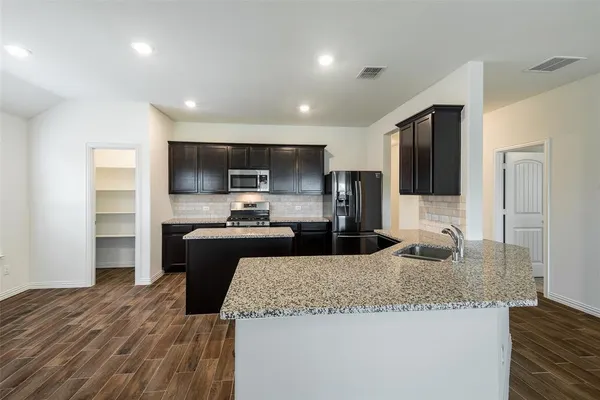 a large kitchen with granite countertop a large counter top stainless steel appliances and cabinets