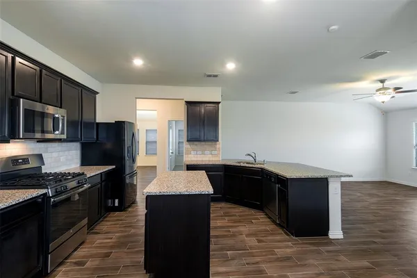 a kitchen with stainless steel appliances kitchen island granite countertop a stove a refrigerator and a sink