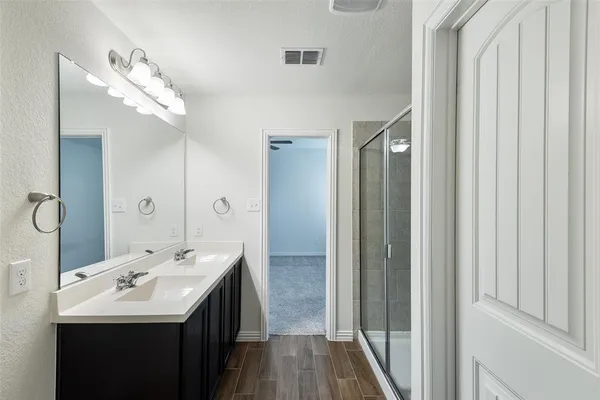 a bathroom with a double vanity sink a large mirror and a shower