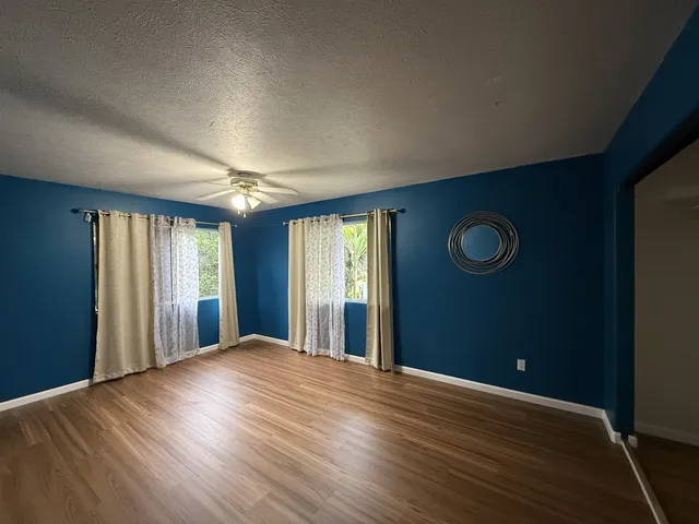 an empty room with wooden floor closet and windows