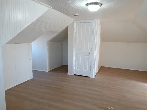 an empty room with wooden floor mirror and windows